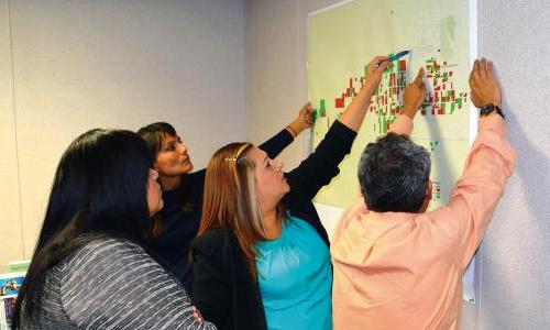 A group of people working at a map hanging on a wall